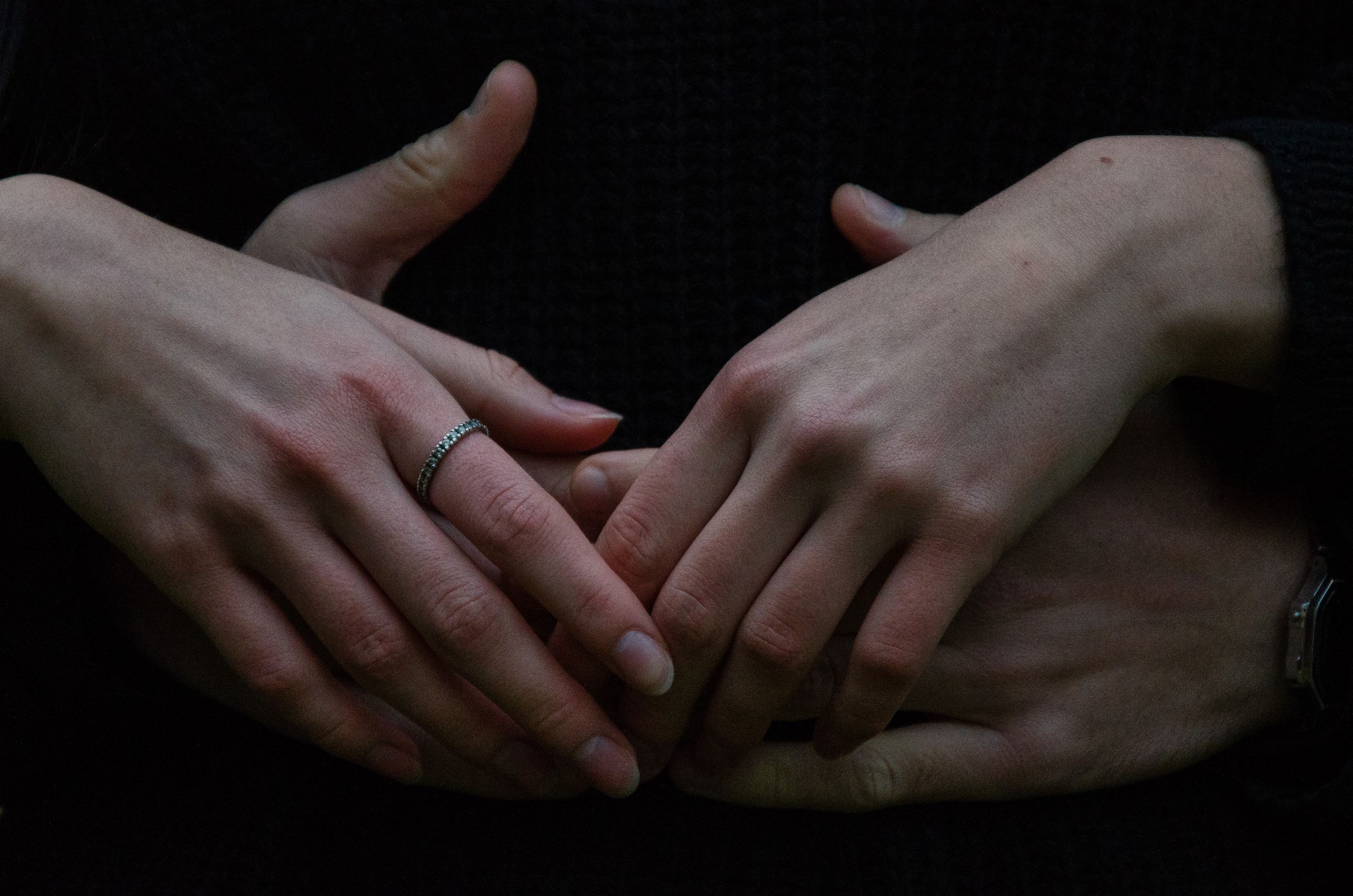 Intimate close-up of a couple's intertwined hands, one with a ring.